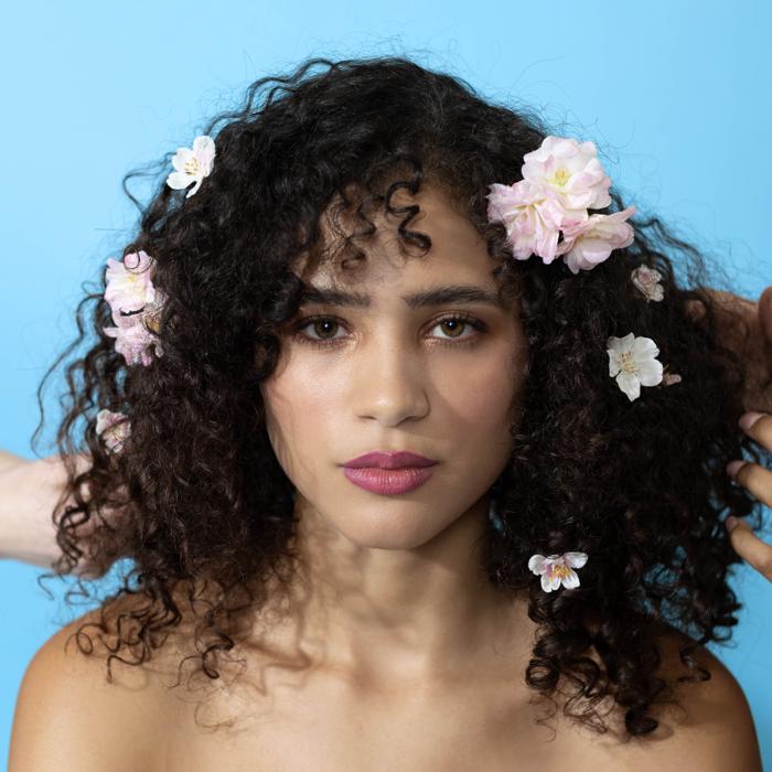 Latinx female model with flowers in hair on blue backdrop photographed by Marty Gottlieb